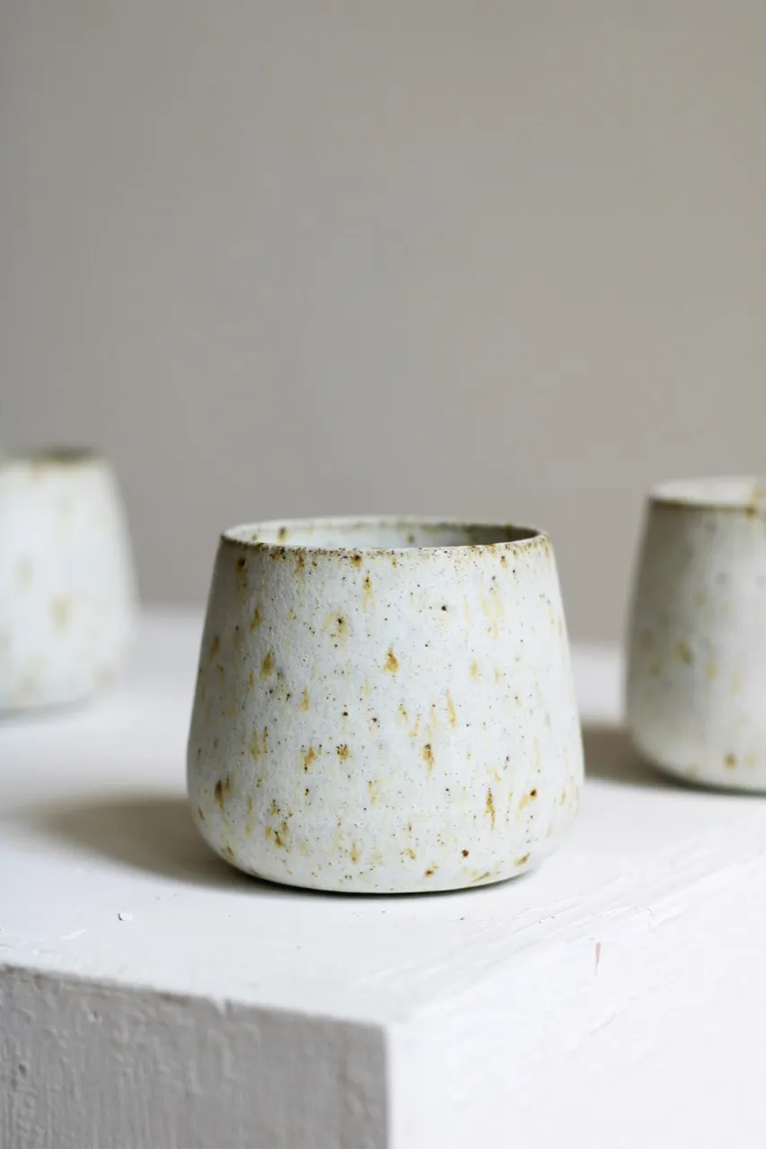 Speckled ceramic cup on a quiet studio surface.